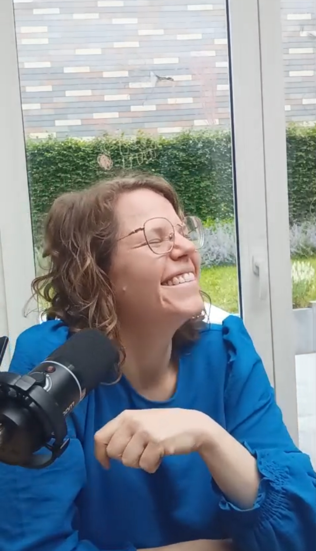 Maike lachend achter een microfoon