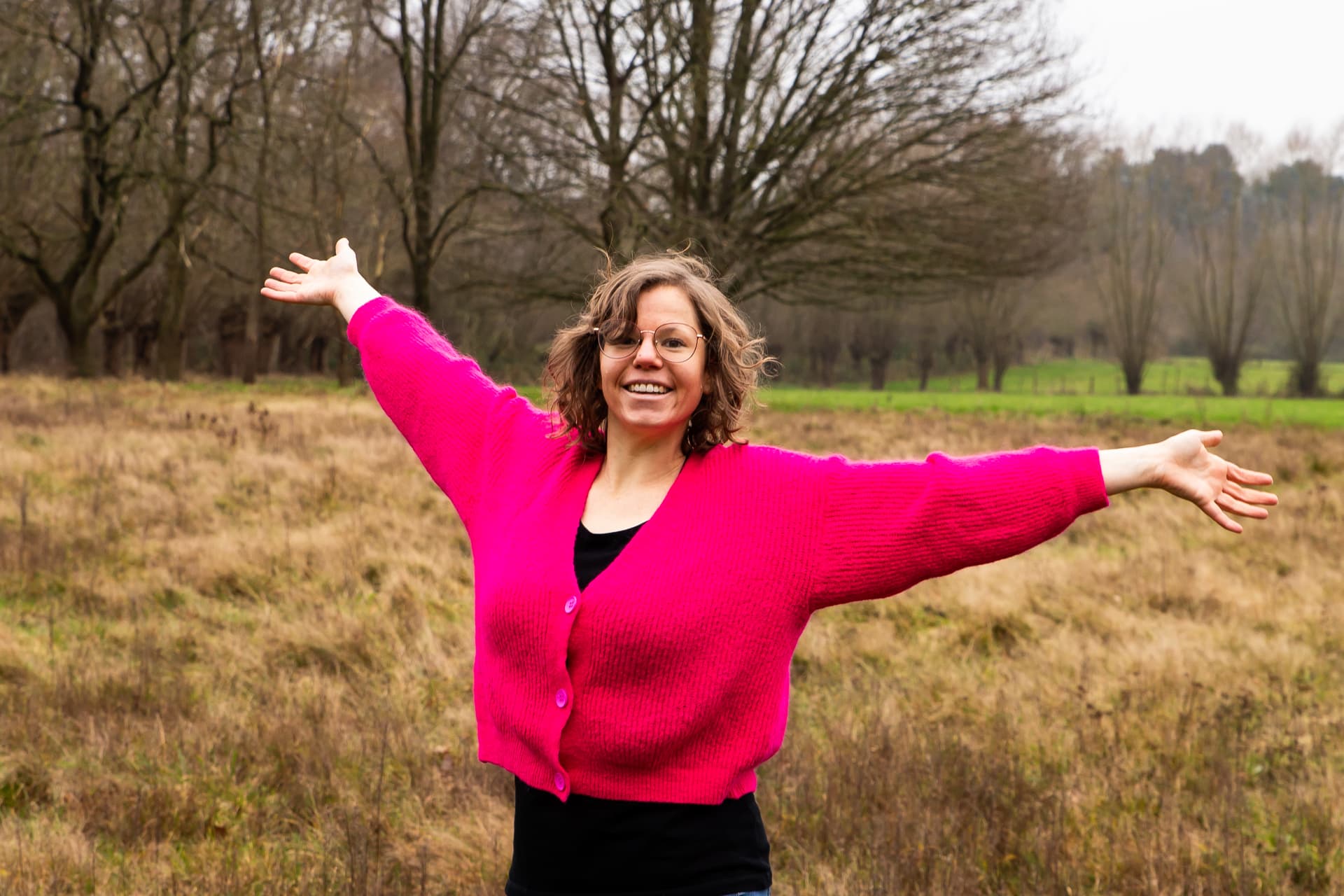 Maike met open armen in een veld