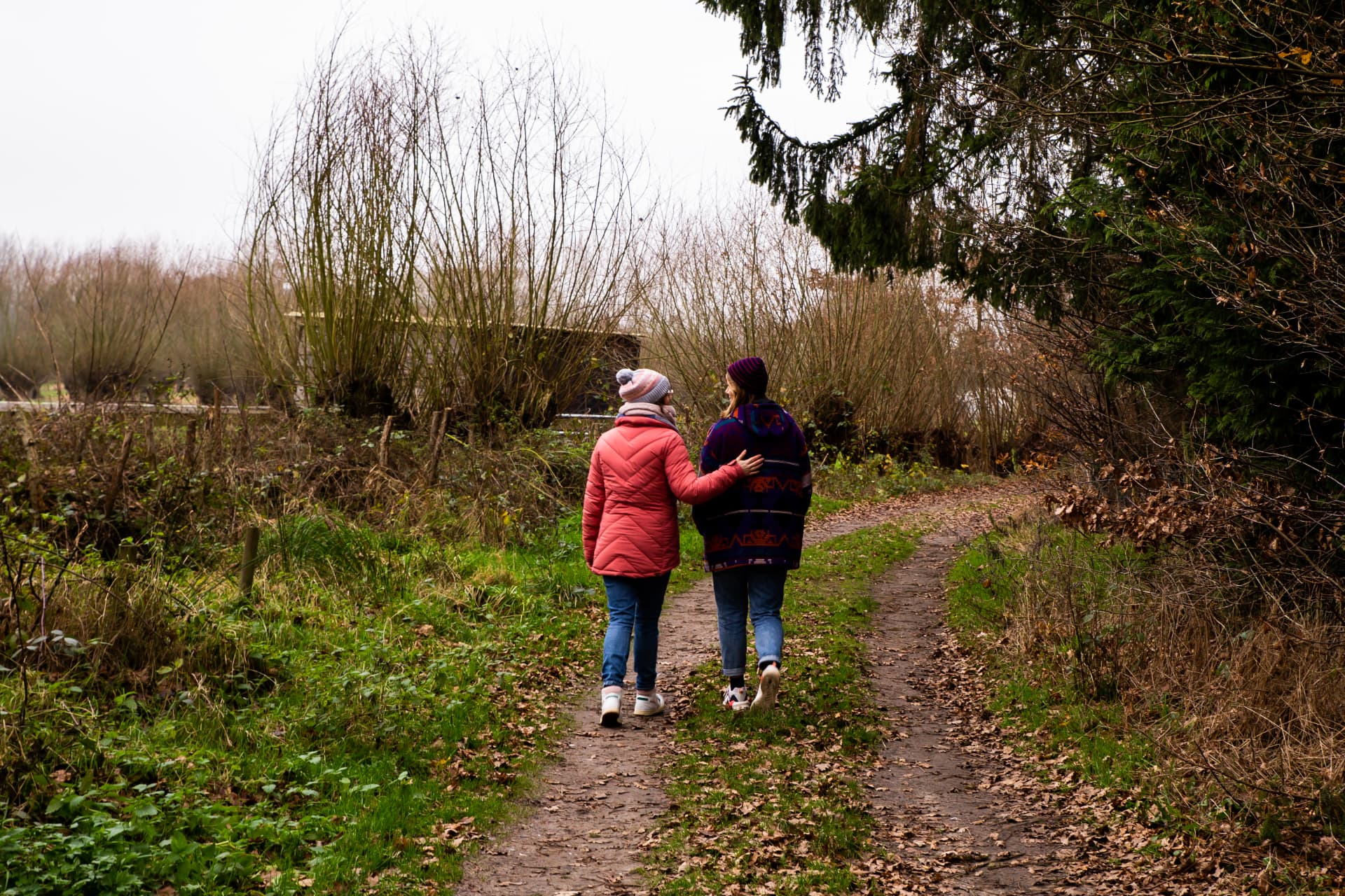 Maike loopt naast iemand en legt steunend een hand op haar rug